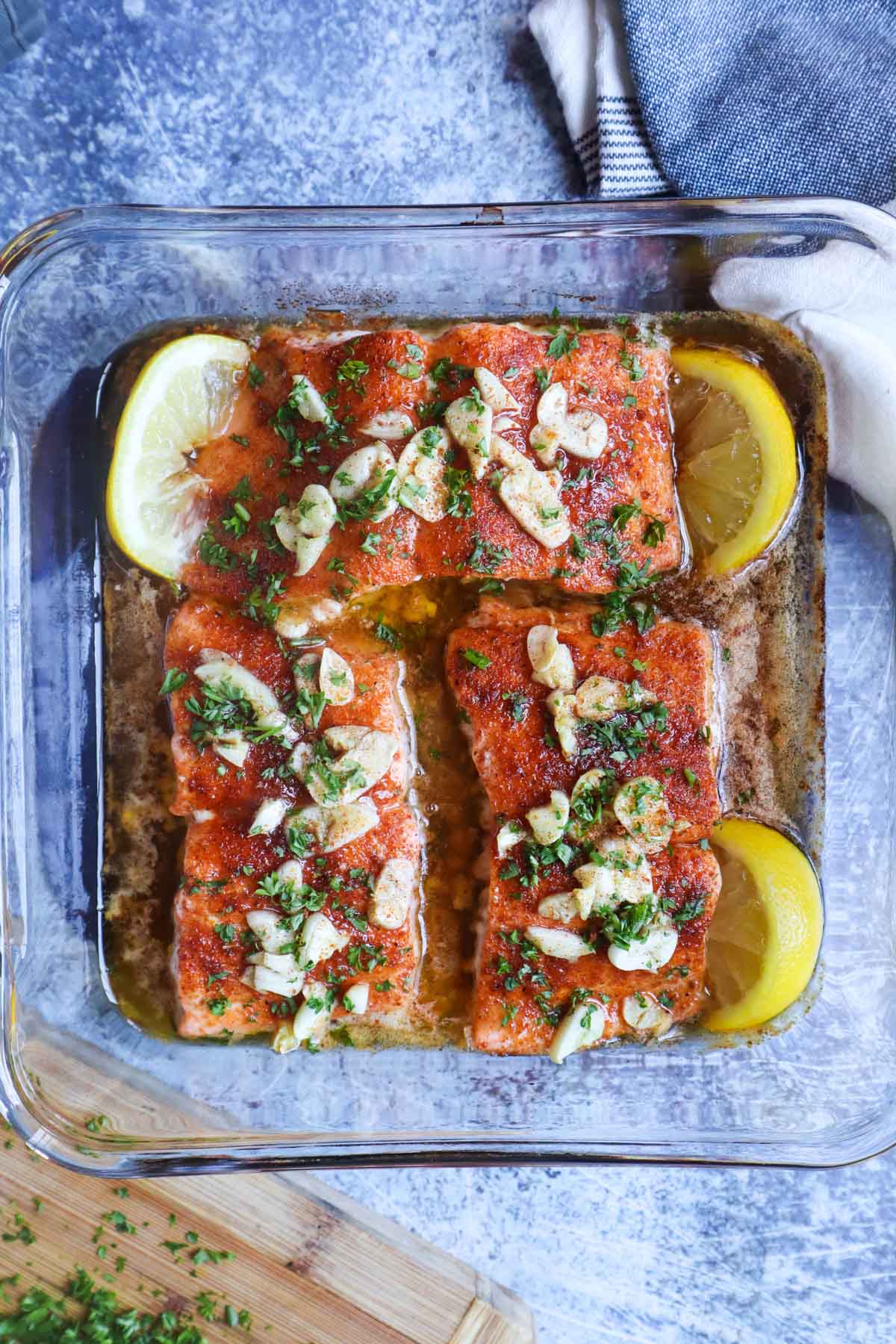 baking dish with 3 salmon filets topped with garlic, parsley, and cajun honey butter sauce