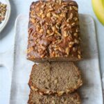4 ingredient banana bread topped with walnuts with two slices cut off of the loaf