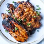 white plate with grilled pulehu chicken breasts topped with green onion