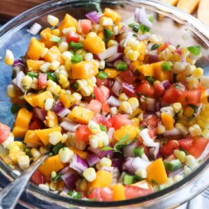 glass bowl with corn mango salsa with red onion, tomatoes, jalapeño, cilantro and more.