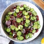 white bowl with beet and cucumber salad topped with a lemon dressing, lemon zest, and feta cheese