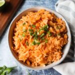 white bowl with gluten free spanish rice topped with fresh cilantro and lime juice