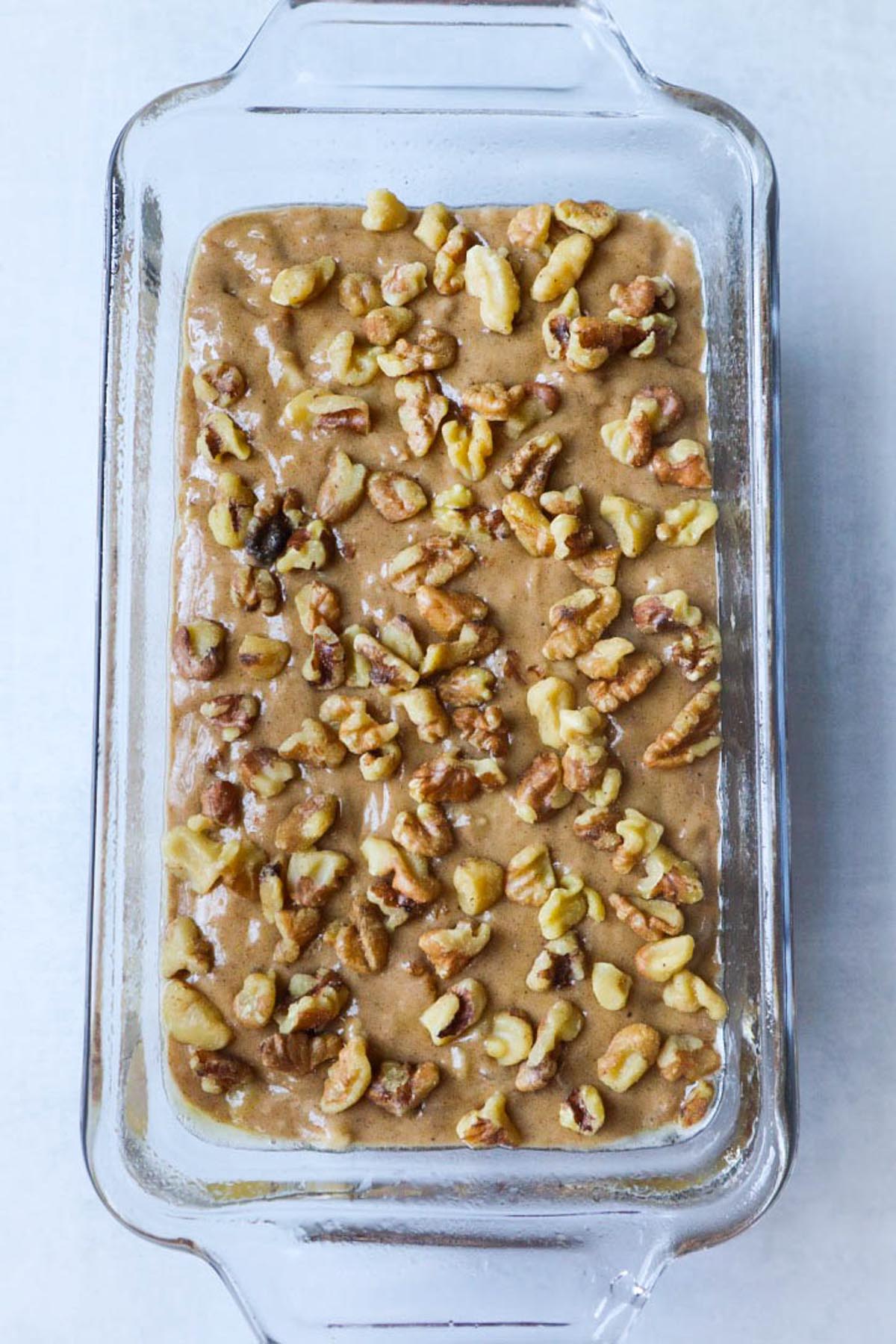4 ingredient banana bread batter topped with walnuts in a glass baking dish