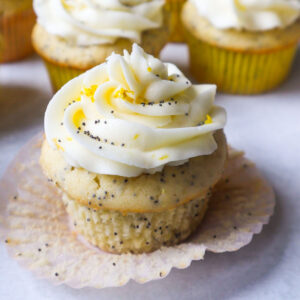 lemon poppyseed cupcake with buttercream icing topped with poppyseeds and lemon zest