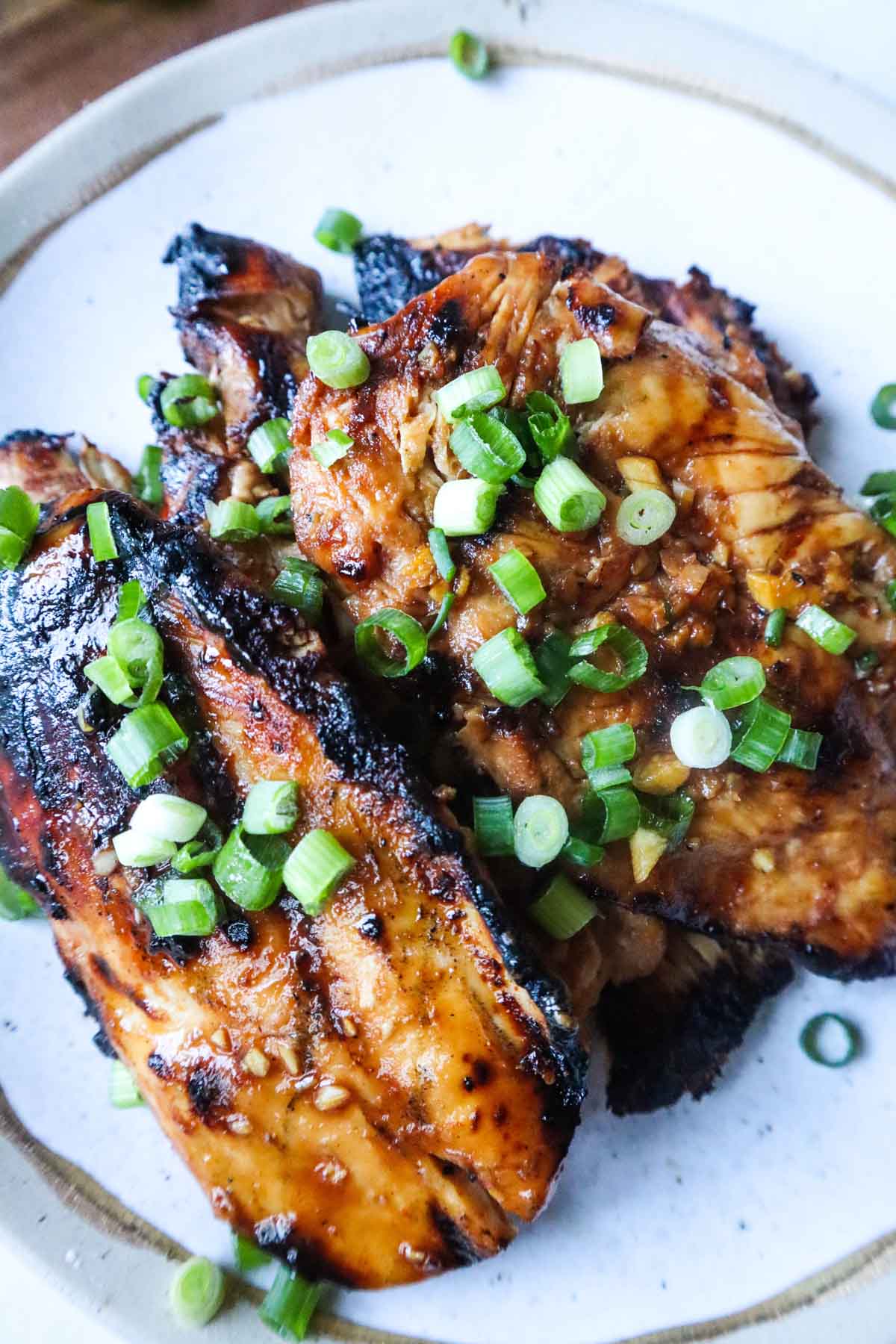 white plate with grilled pulehu chicken breasts topped with green onion