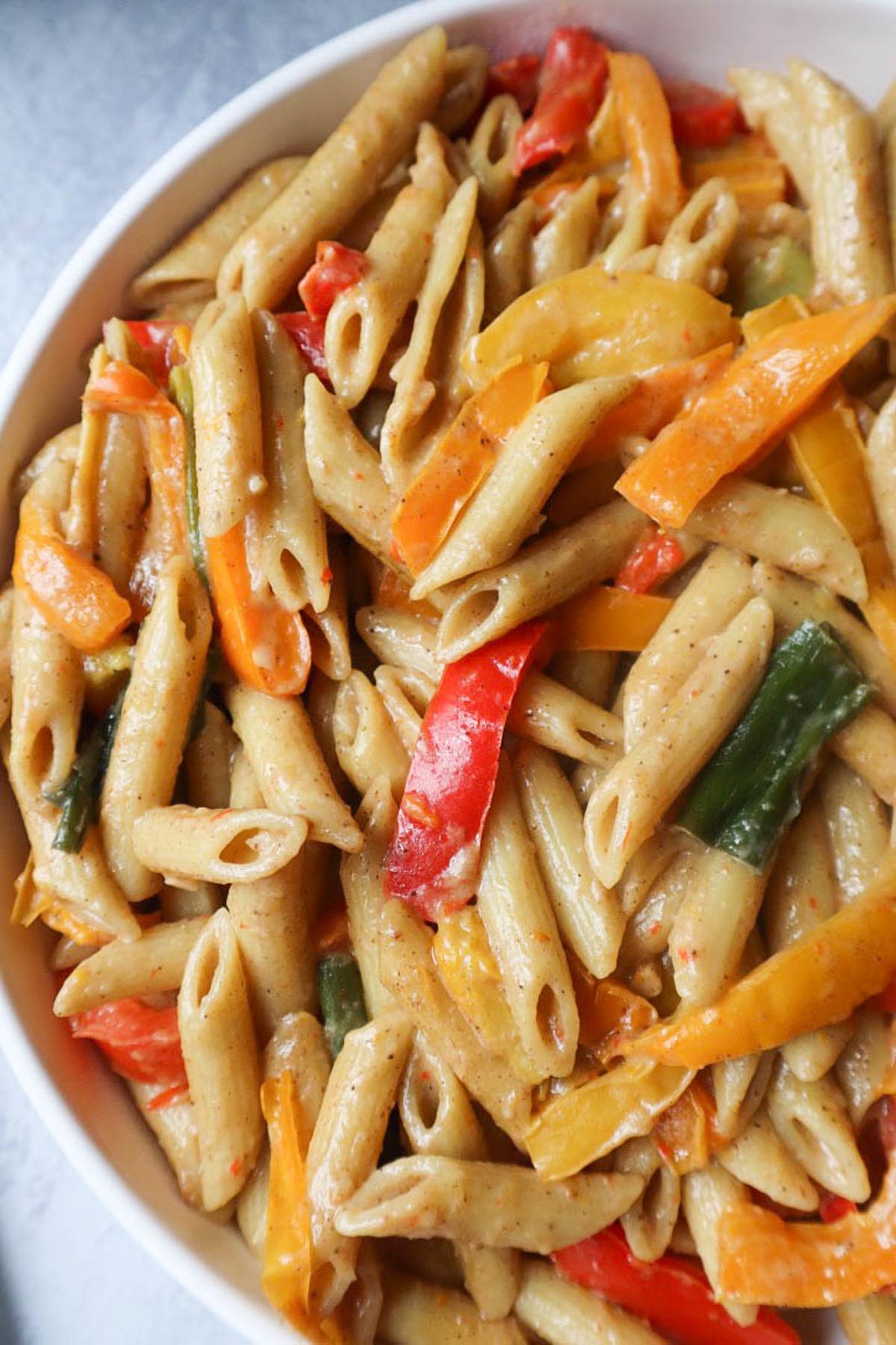 up close image of rasta pasta with red and orange peppers with green onion