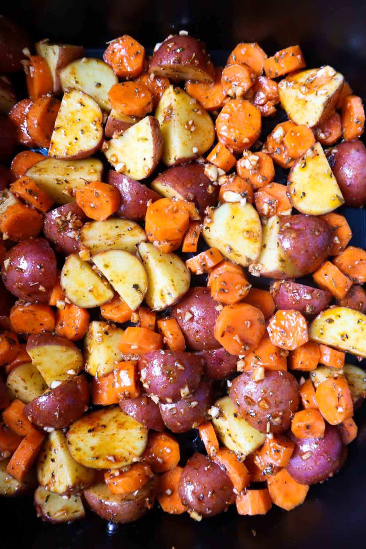 air fryer basket with seasoned potatoes and carrots before they're cooked
