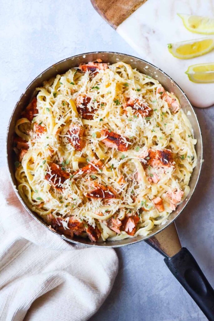 skillet with fettuccine alfredo topped with parmesan and cajun salmon