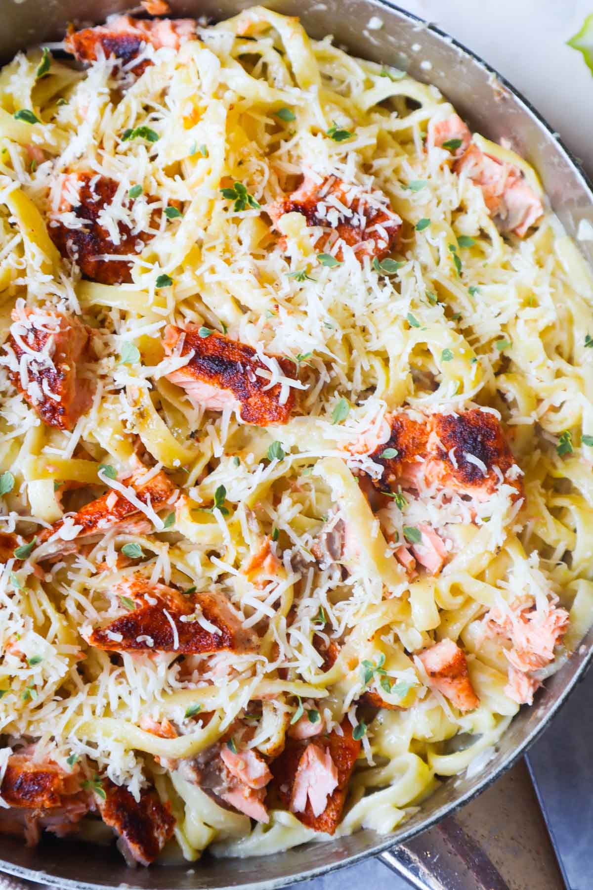 skillet with fettuccine alfredo topped with parmesan and cajun salmon