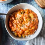 a bowl of butter bean curry topped with fresh cilantro and coconut cream on a bed of basmati rice