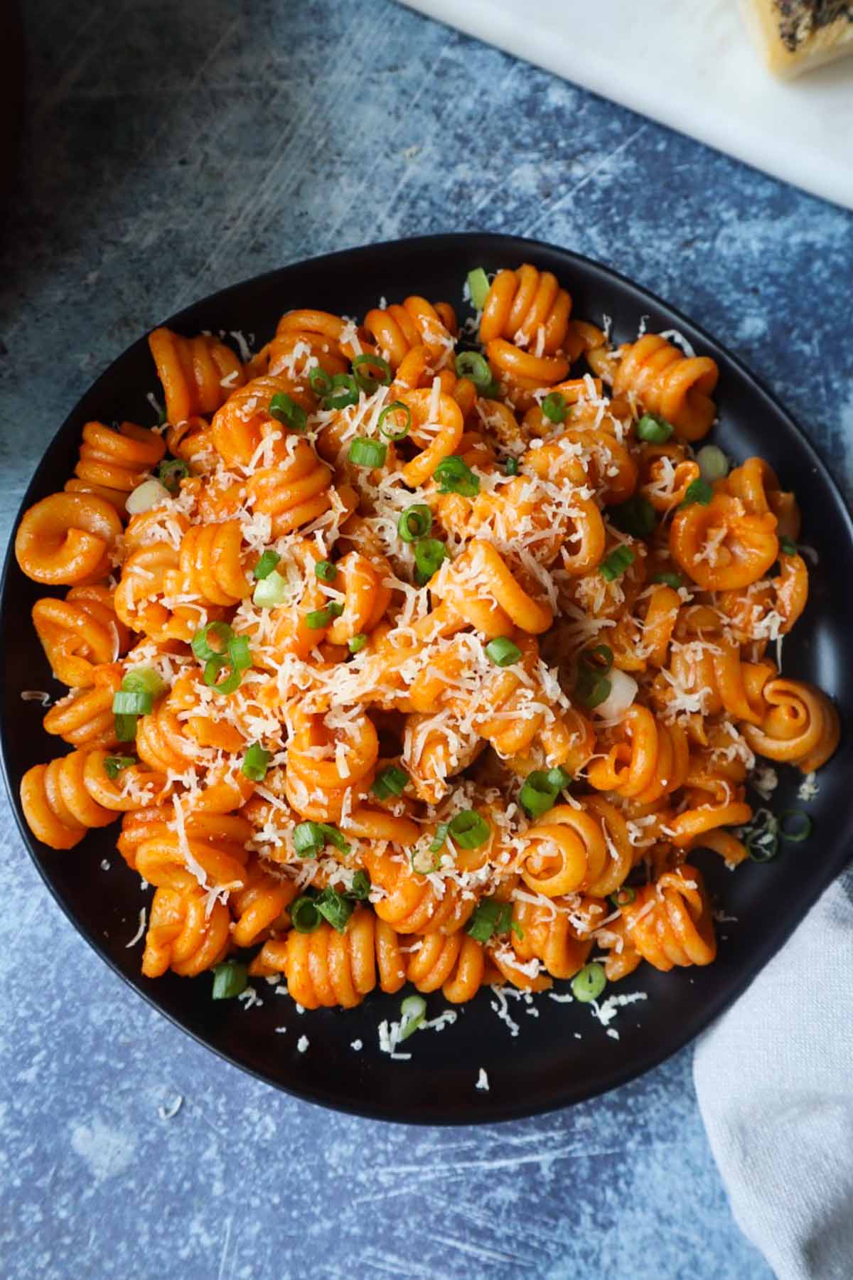 black plate with gochujang pasta with a blue background