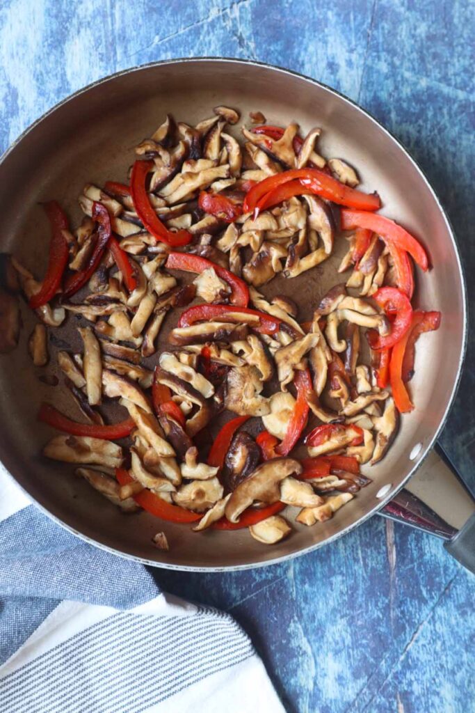 skillet with sautéed chopped red bell pepper and mushrooms