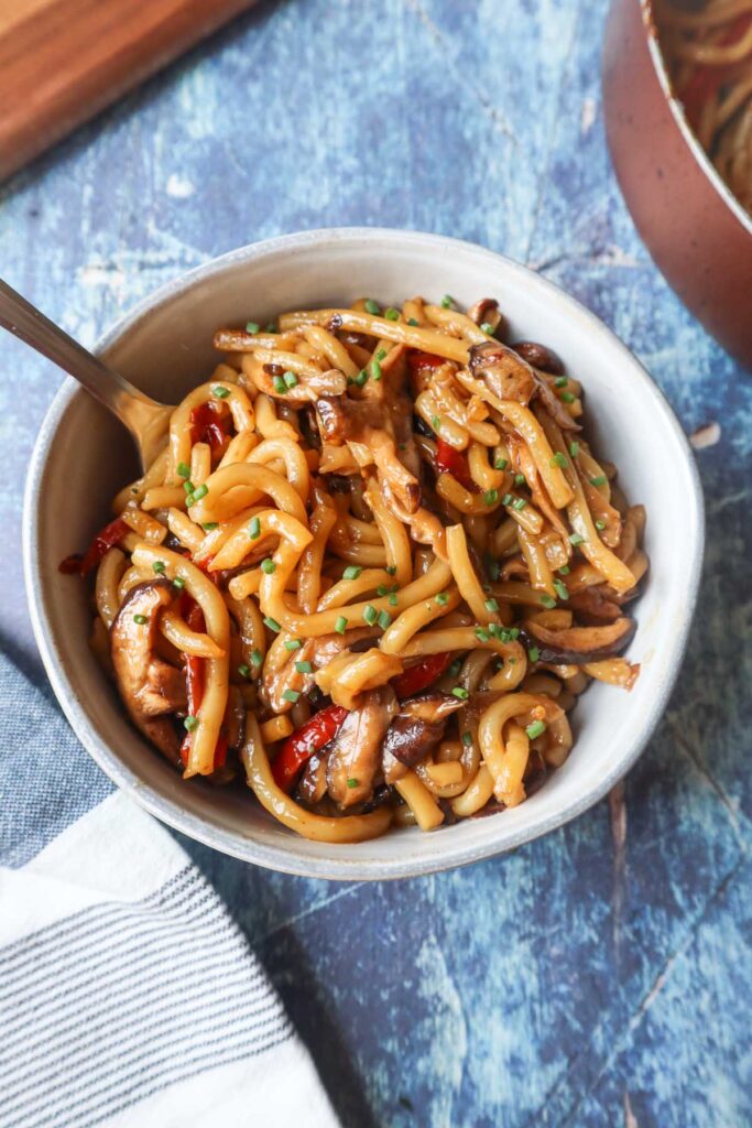 bowl and fork with teriyaki udon with red pepper and mushrooms