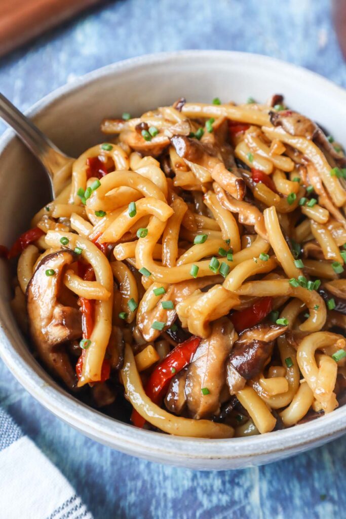 bowl with teriyaki udon topped with chives and made with red pepper and mushrooms