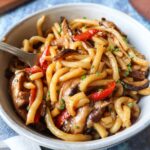 bowl with teriyaki udon topped with chives and made with red pepper and mushrooms