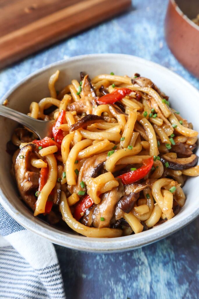 bowl with teriyaki udon topped with chives and made with red pepper and mushrooms