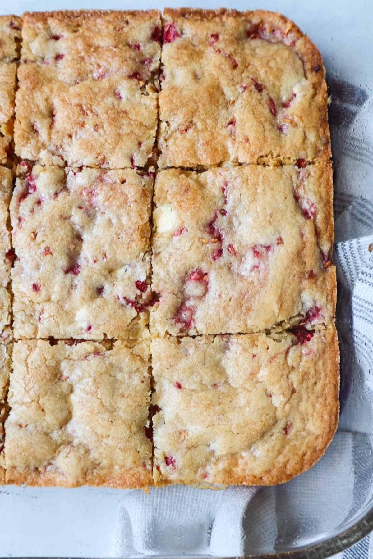 glass baking dish with cooked white chocolate raspberry blondie cut into equal squares