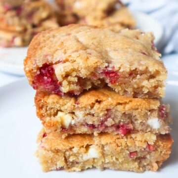 blondies with white chocolate chips and raspberries stacked on top of each other