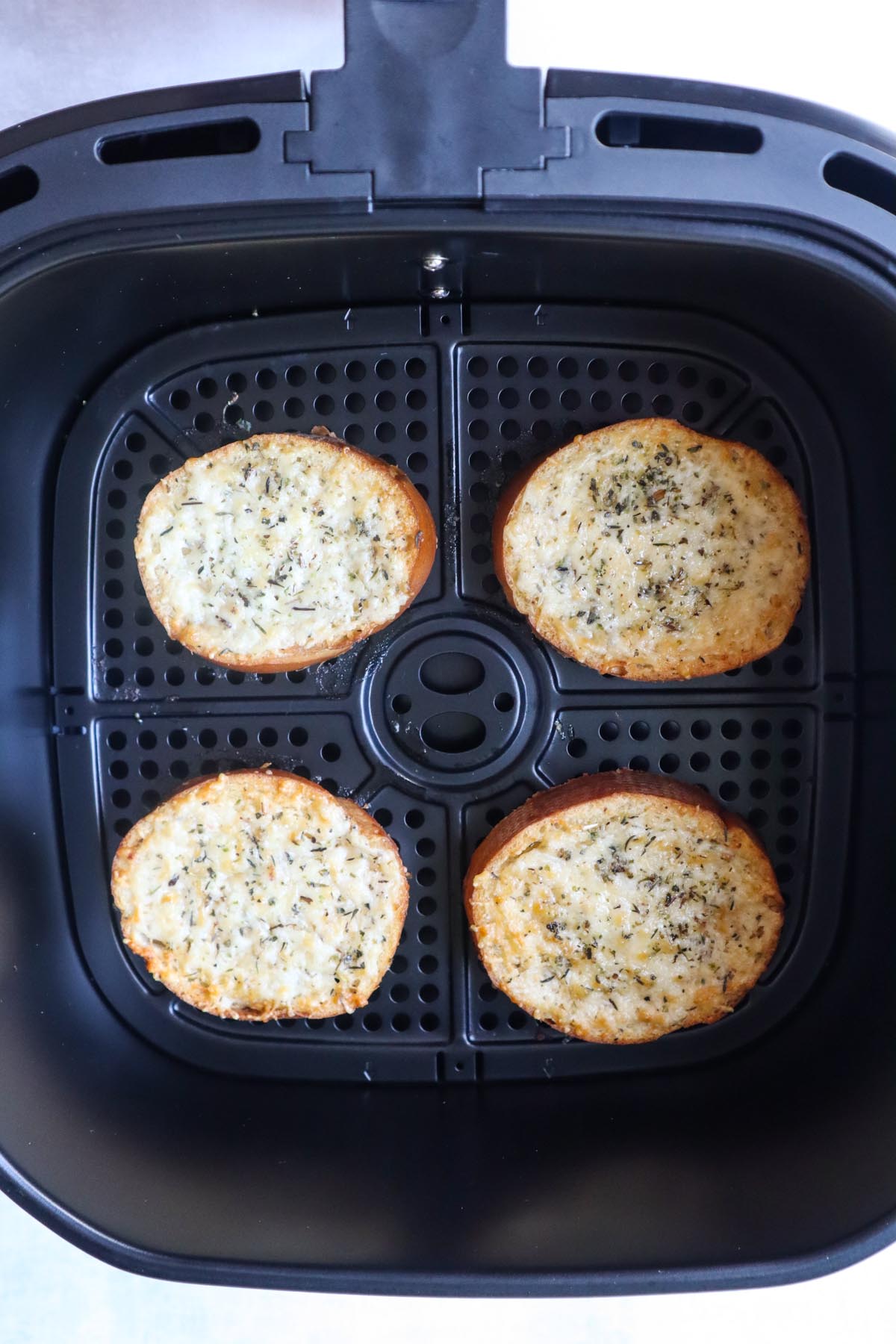 air fryer with four slices of cheese toast right after it's been cooked and the cheese is melted