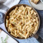 skillet with truffle rigatoni topped with shredded cheese and fresh thyme