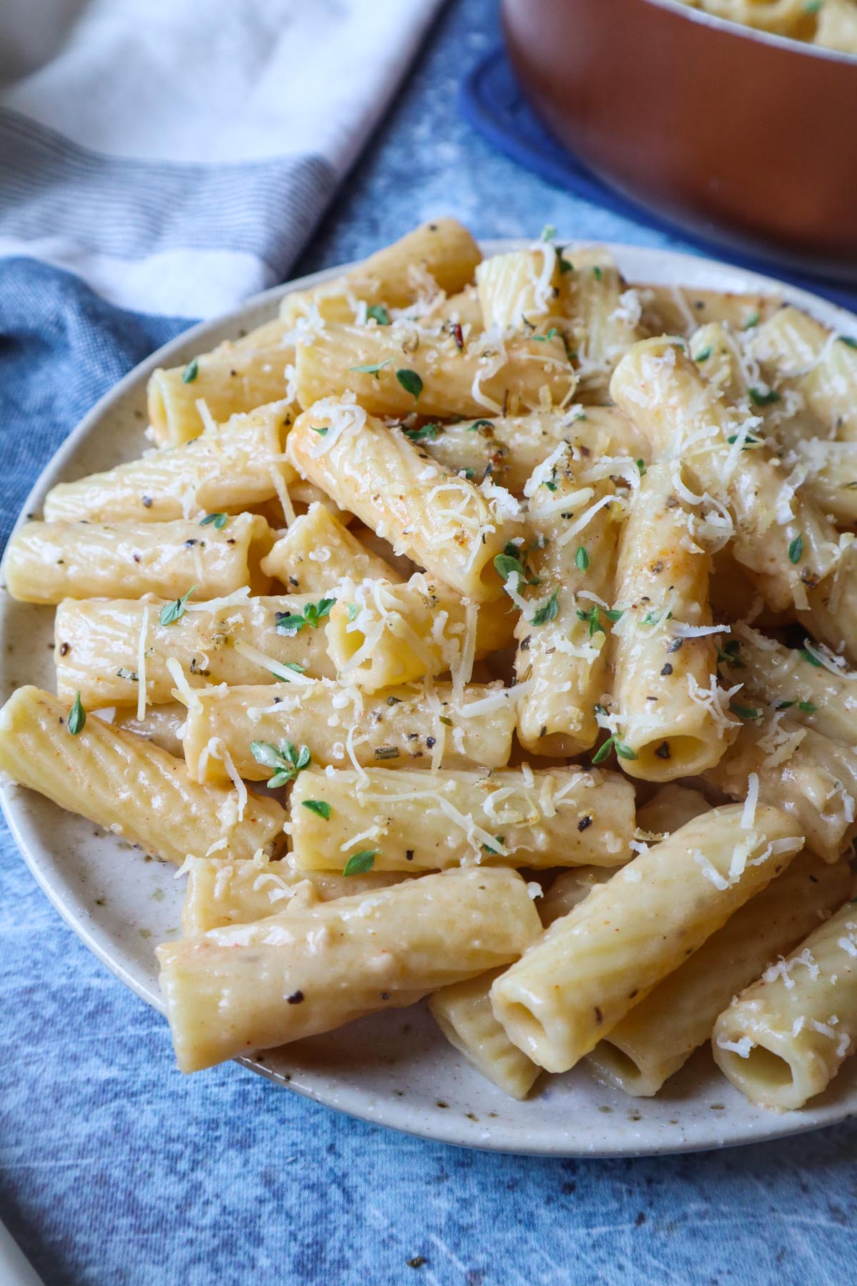 white plate with truffle rigatoni topped with cheese and fresh thyme