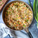 skillet with tuna fried rice with chopped vegetables and scallions
