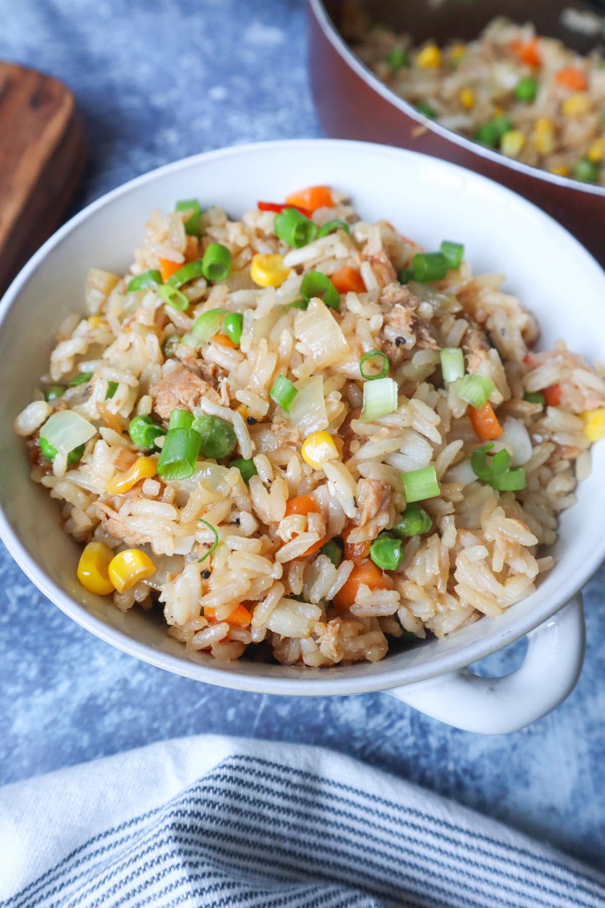 white bowl of fried rice with tuna mixed with vegetables and topped with scallions