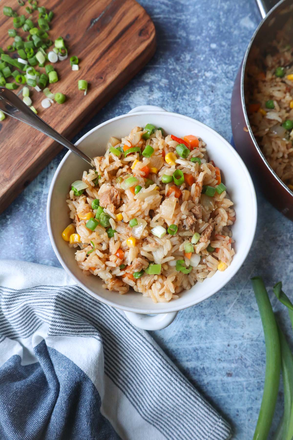 white bowl of fried rice with tuna mixed with vegetables and topped with scallions