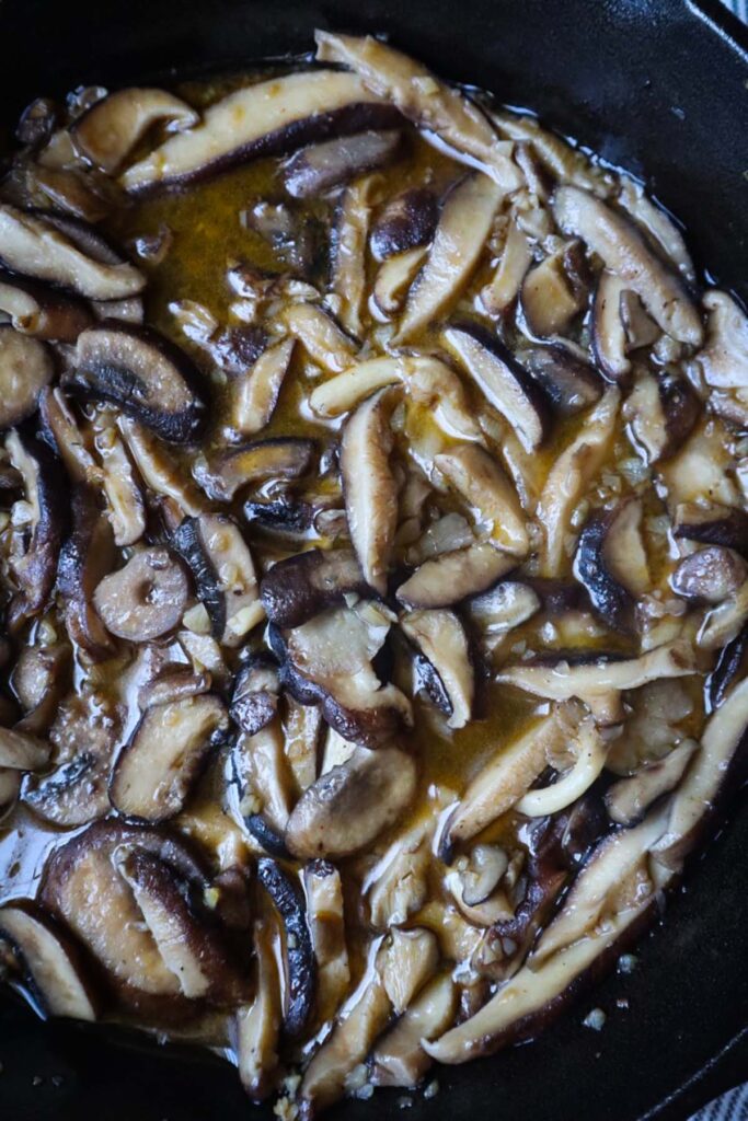 cast iron skillet with sauteed sliced mushrooms with a savory sauce
