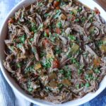 white bowl with juicy shredded tinga de res with tomatoes and onion topped with fresh cilantro