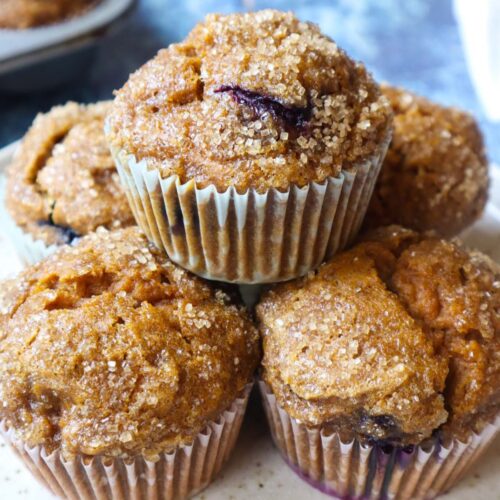 pumpkin blueberry muffins stacked and topped with turbinado sugar