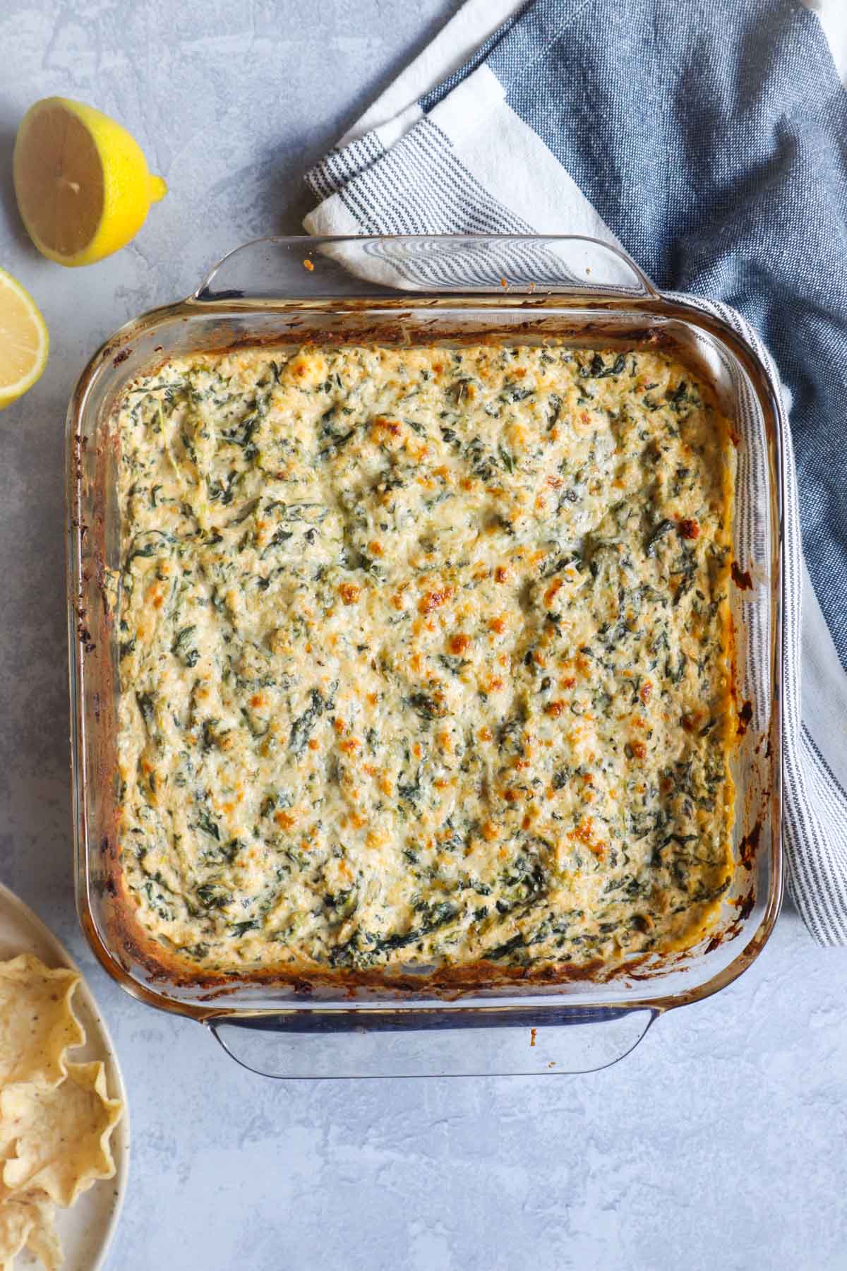 spinach crab dip in glass baking dish topped with golden brown cheese