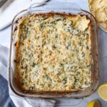 spinach crab dip in glass baking dish topped with golden brown cheese