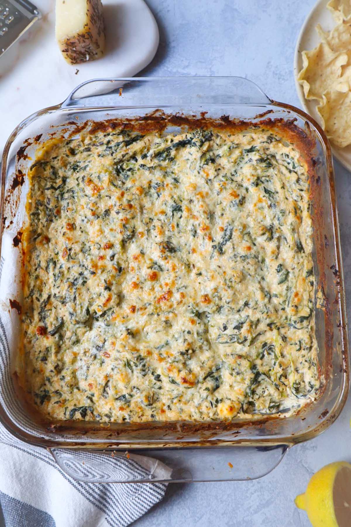 spinach crab dip in glass baking dish topped with golden brown cheese