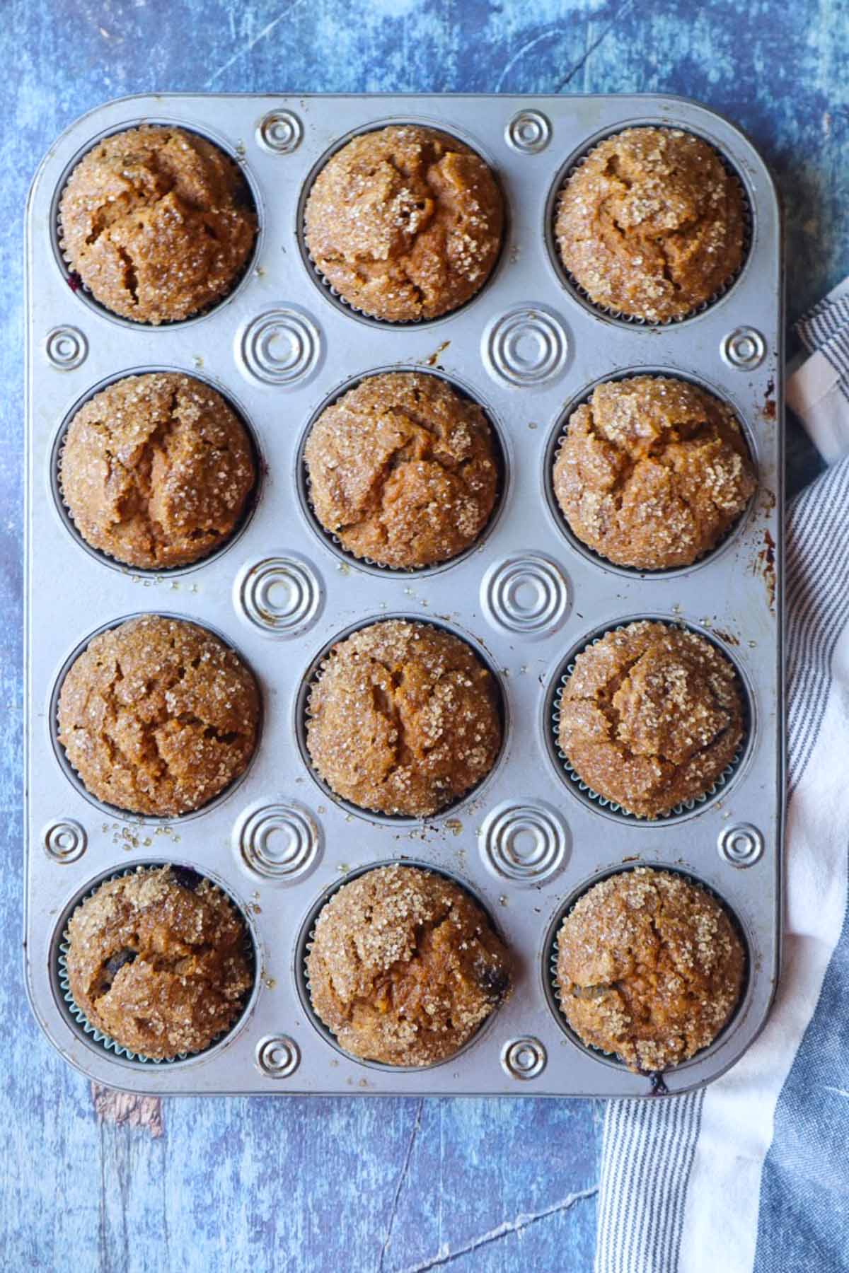 muffin tin with cooked pumpkin blueberry muffins topped with turbinado sugar