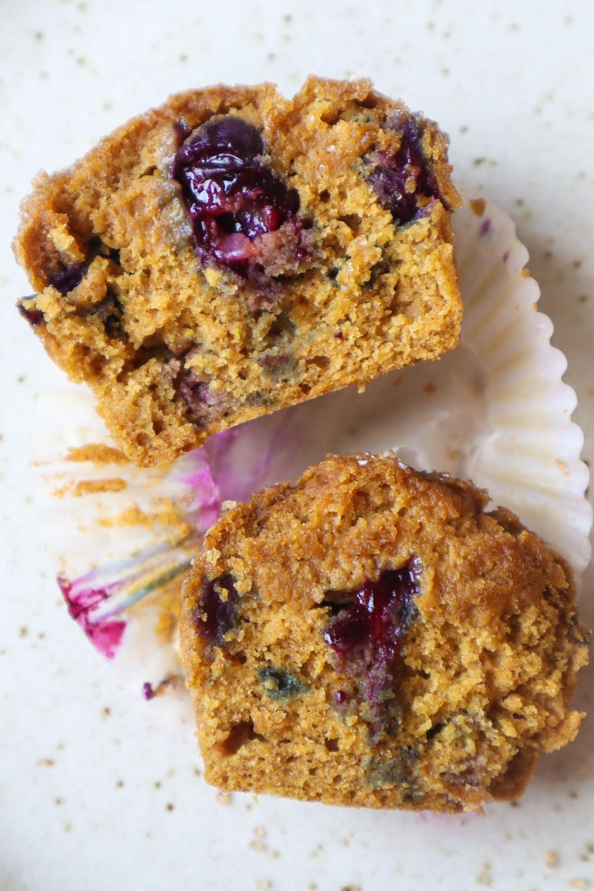 pumpkin blueberry muffin sliced in half showing a juicy blueberries in the middle