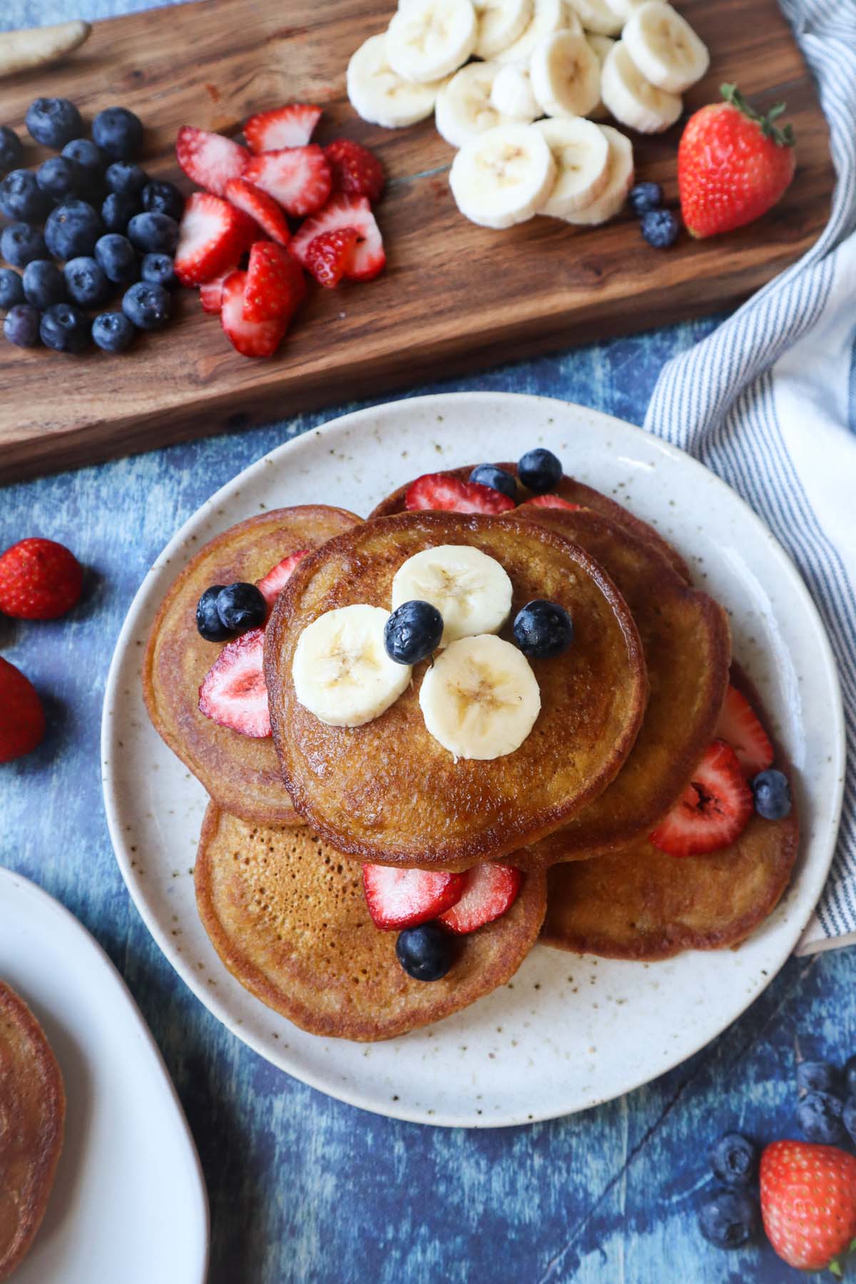 white plate with pumpkin pancakes topped with banana, blueberries, and strawberries