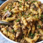 white plate with french onion pasta topped with fresh parsley