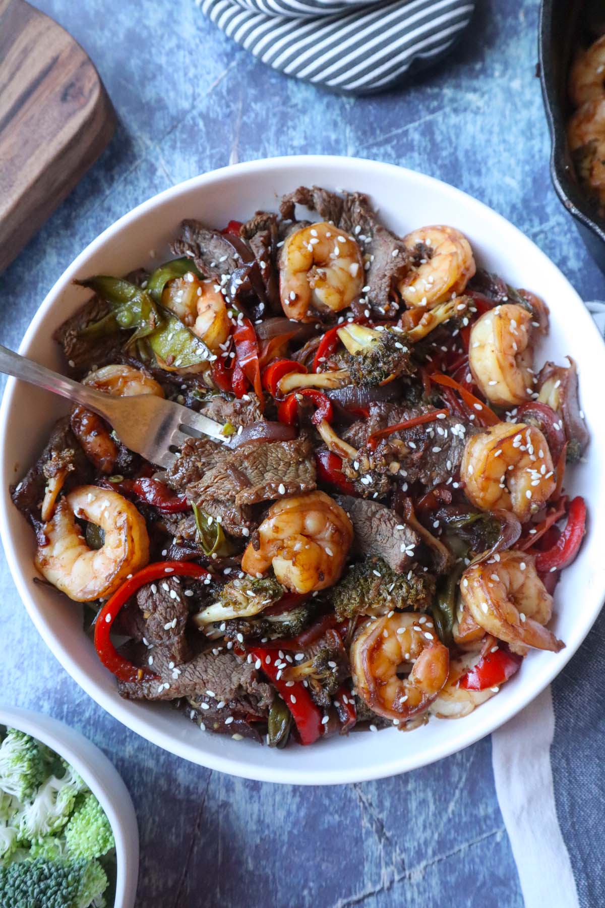 white plate with shrimp and steak stir fry topped with sesame seeds