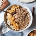 white bowl with oatmeal topped with cooked apples and sliced almonds