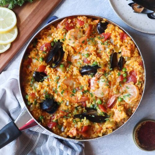 skillet with paella topped with shrimp and mussels