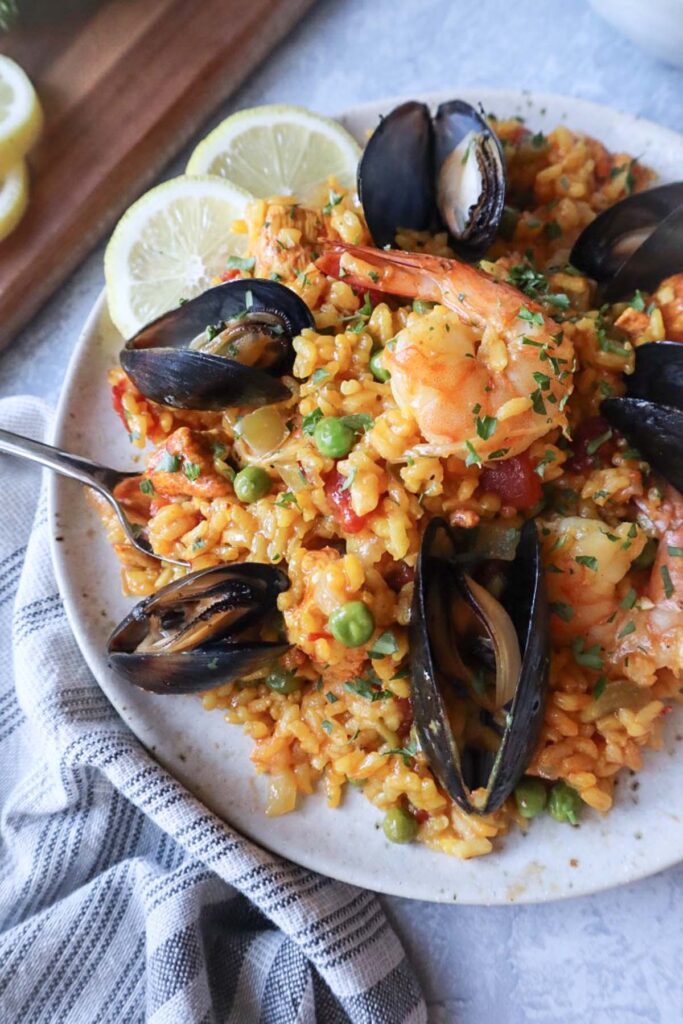 white plate with paella topped with mussels and shrimp