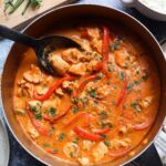 skillet with cooked Thai chicken curry with spoon scooping pieces of chicken.