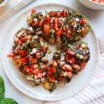 white plate with cooked chicken topped with bruschetta and balsamic glaze.