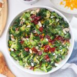 white glass bowl with beetroot broccoli salad topped with orange zest, almonds, and feta.
