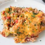 white plate topped with stuffed bell pepper casserole topped with melted cheese and parsley.