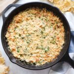 cast iron skillet with baked spinach artichoke dip.