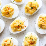 plate with dairy free deviled eggs topped with paprika and minced parsley.