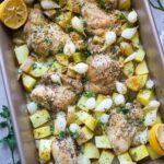 baking dish with roasted chicken thighs, potatoes, and pearl onion topped with parsley.