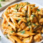 white plate with creamy chicken curry pasta topped with cilantro.